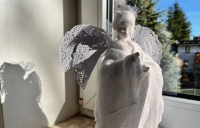 Figurka białego anioła na tle okna